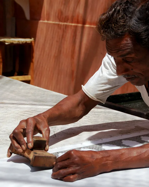 A hand-carved wooden printing block being laid onto cloth.