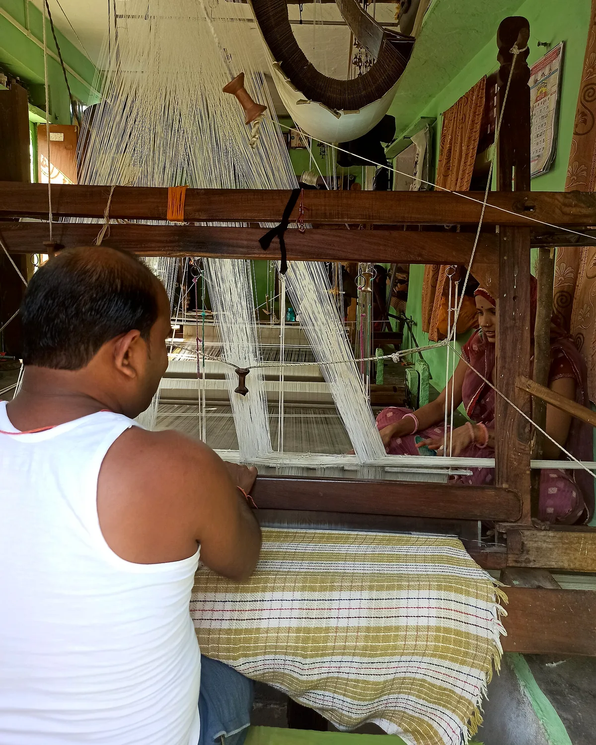 A weaver at the bench, a part-woven sari stretched in front of him.