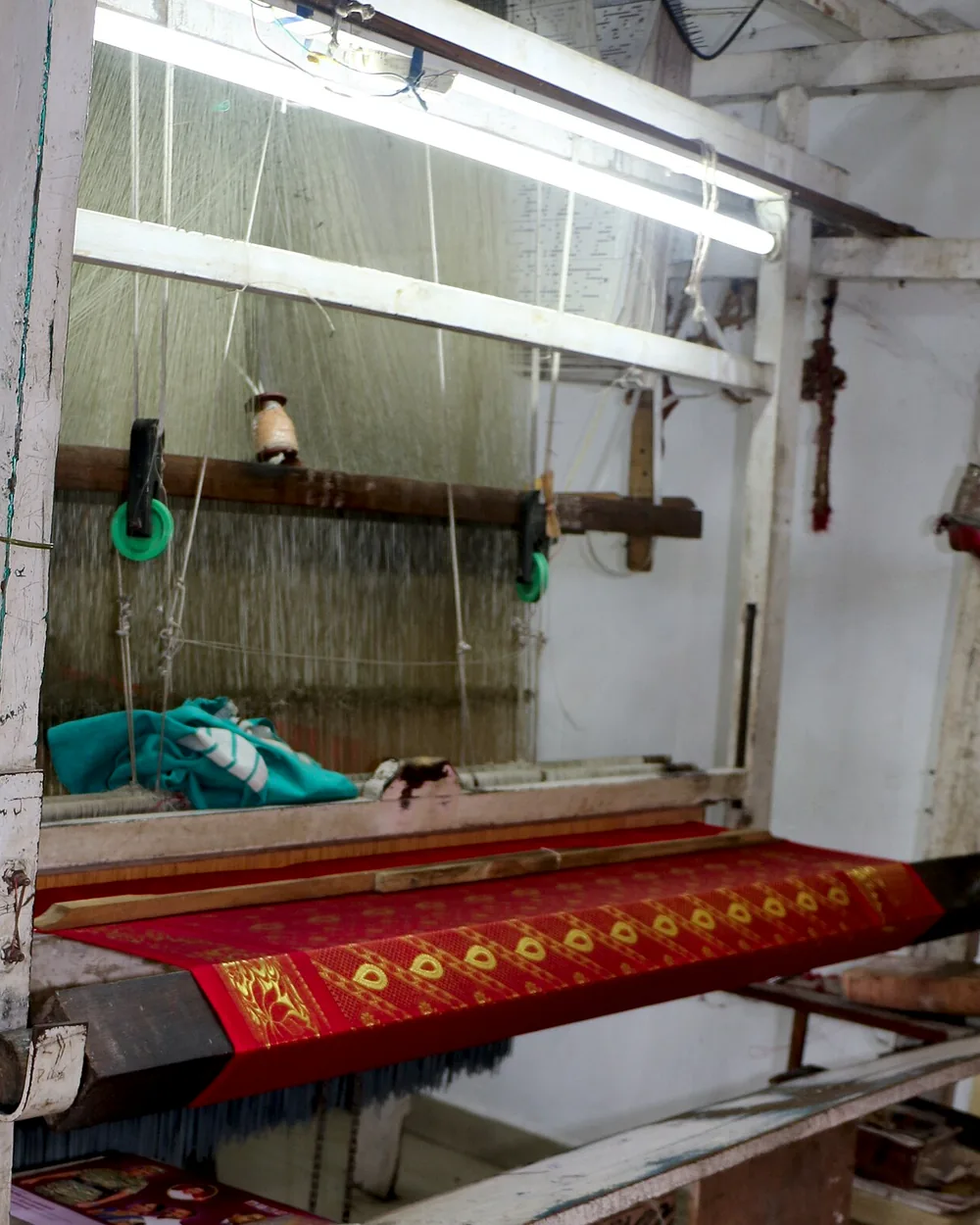 A pit loom part-way through a sari, the warp threads stretched under tension.