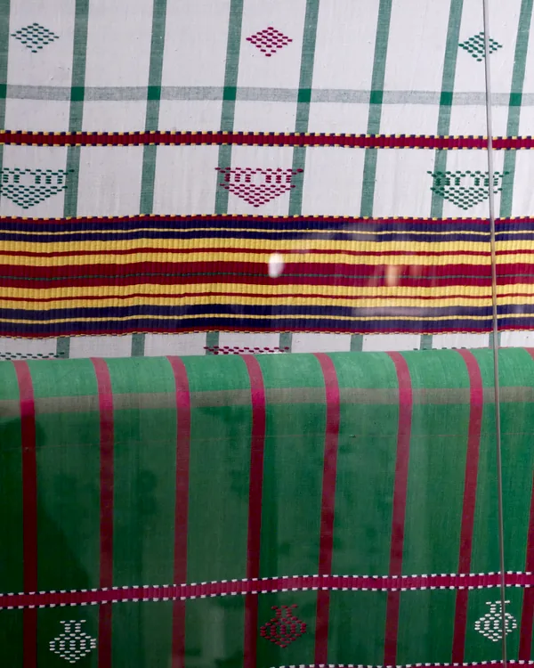 Woven cloth in green and madder stripes, still on the loom.