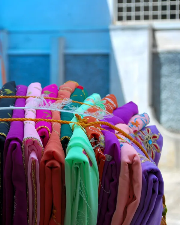 Saris in every colour stacked on a vendor's rail.