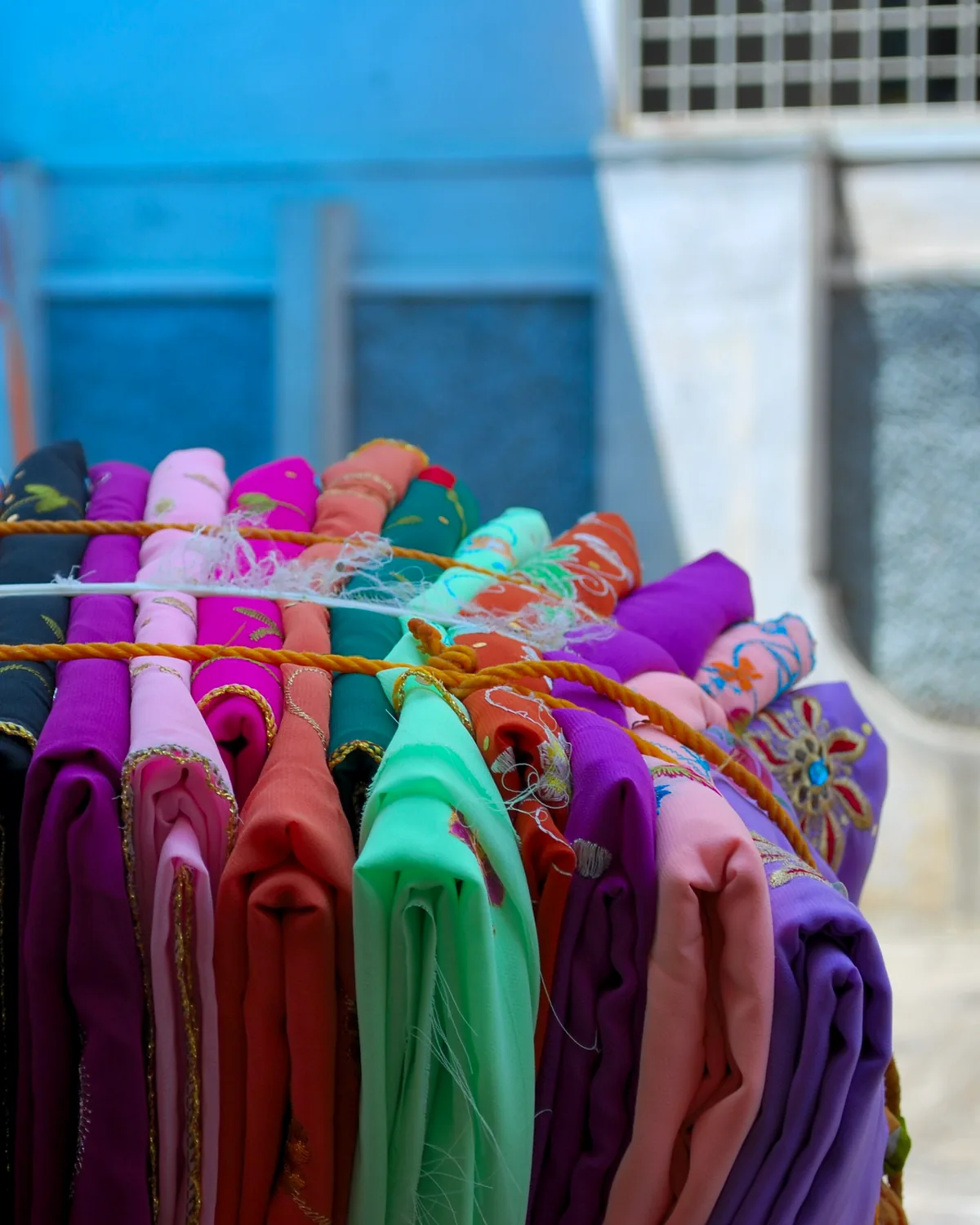 Saris in every colour stacked on a vendor's rail.