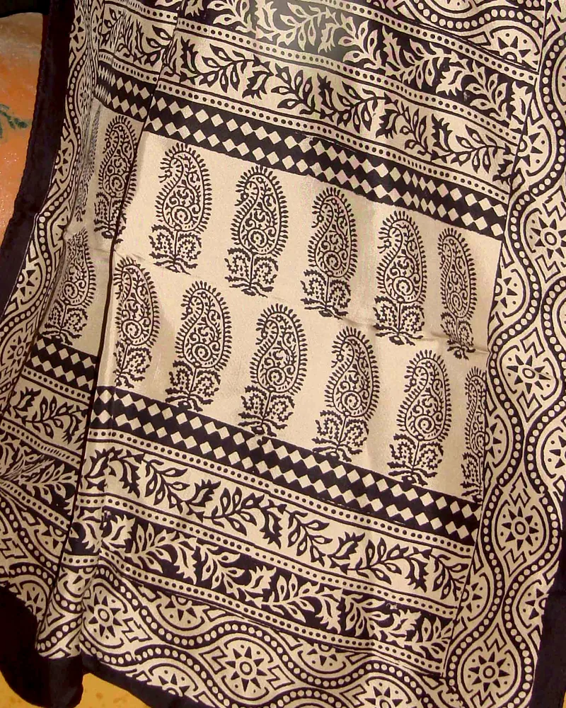 A Bagh-print stole in iron-black paisley on cream, folded to show its banded border.