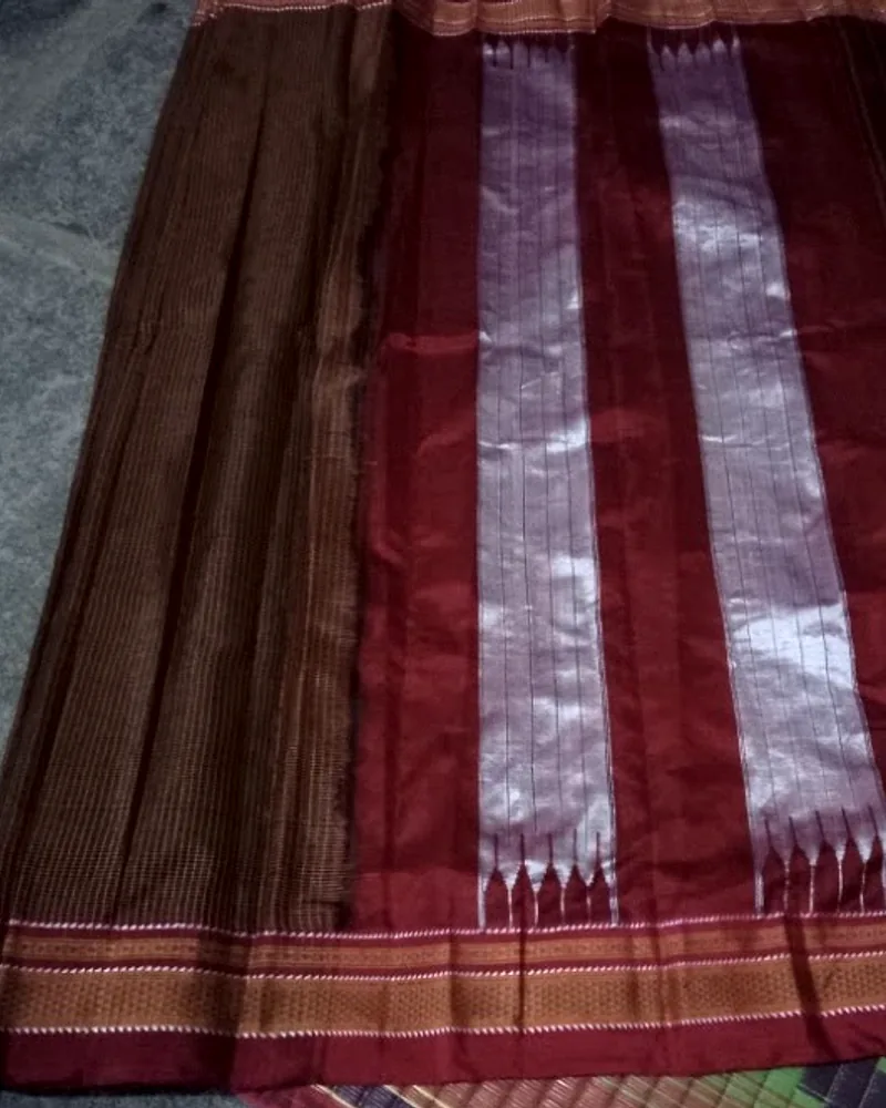 An Ilkal sari laid out, bronze striped body beside a red silk pallu banded in silver.
