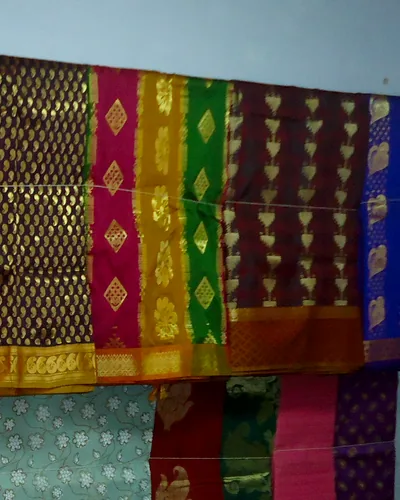 Kanchipuram silk saris on a rail, each with a wide woven gold border.