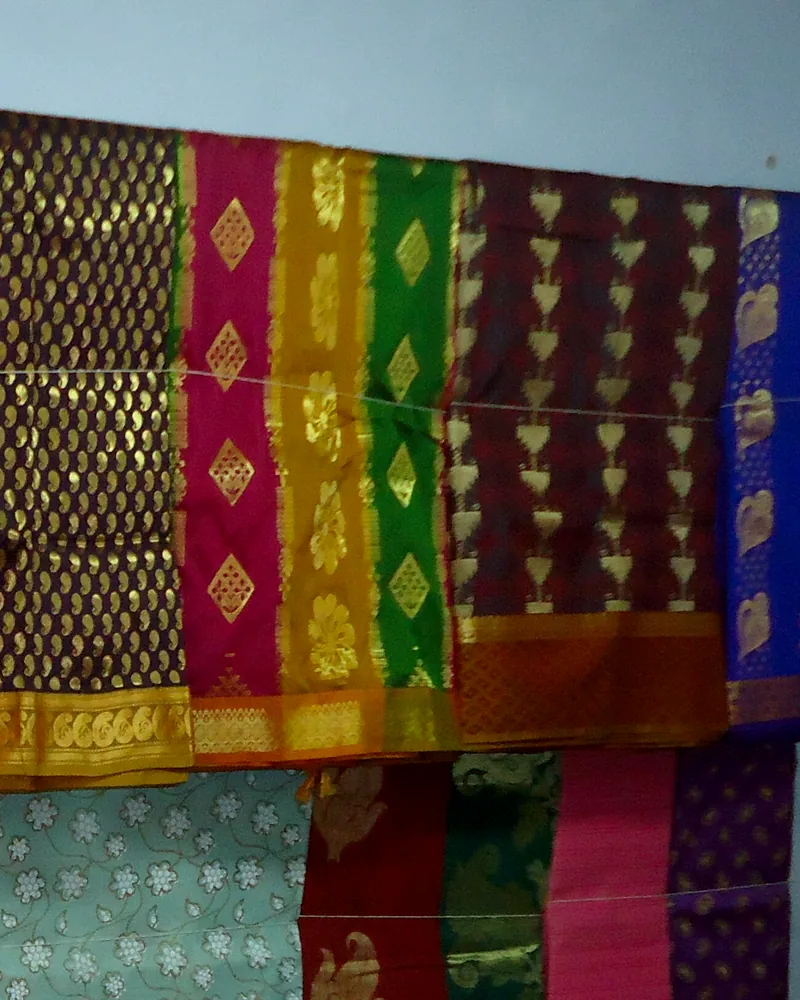 Kanchipuram silk saris on a rail, each with a wide woven gold border.