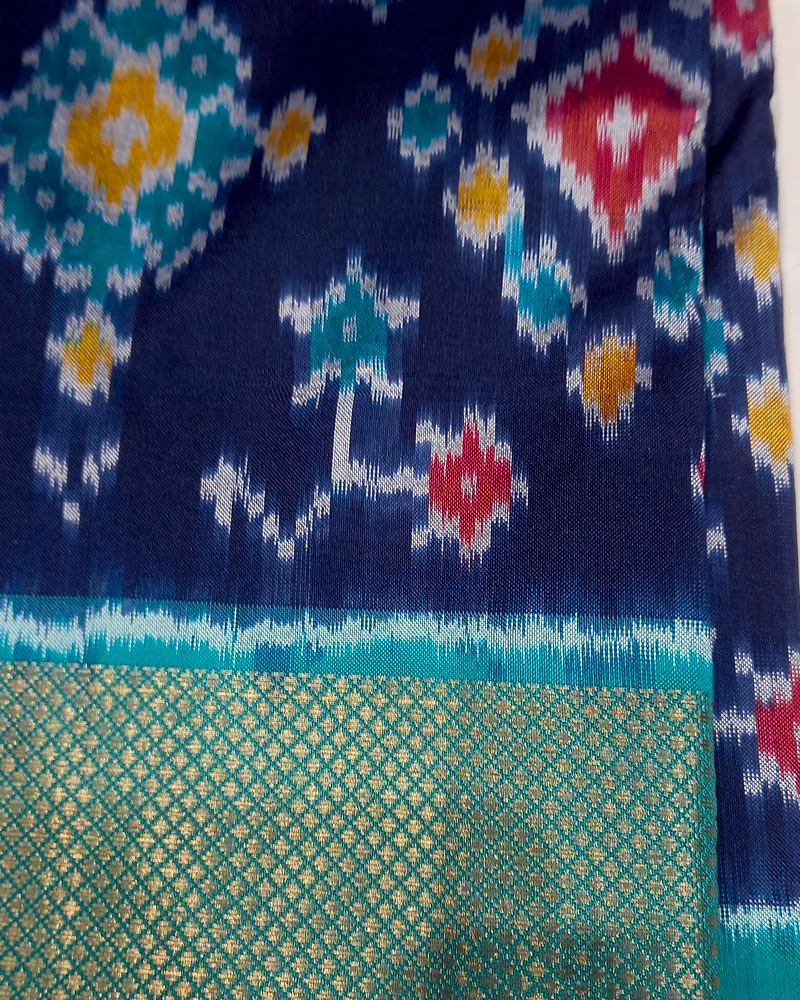 An indigo Pochampally ikat sari with stepped diamond motifs and a teal and gold border.