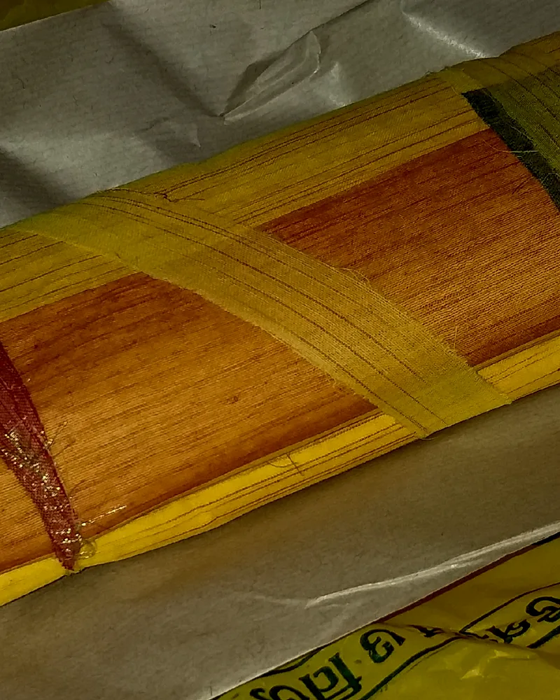 A folded Bengal tant sari in mustard cotton with a narrow woven border.