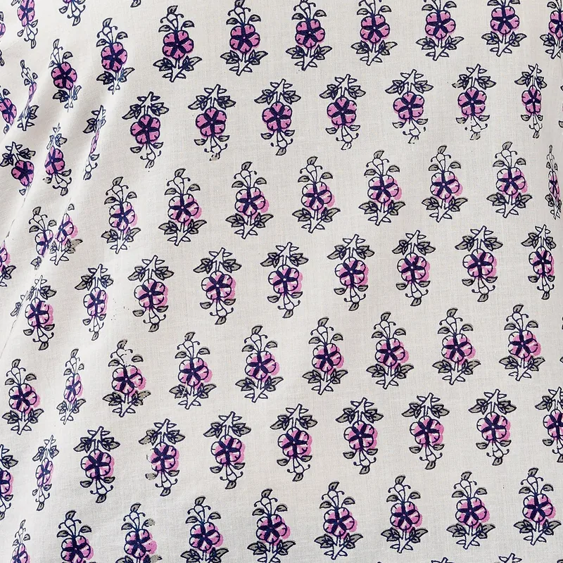 Bagru hand-block cotton — rows of small violet and rose floral butis on an undyed ground.