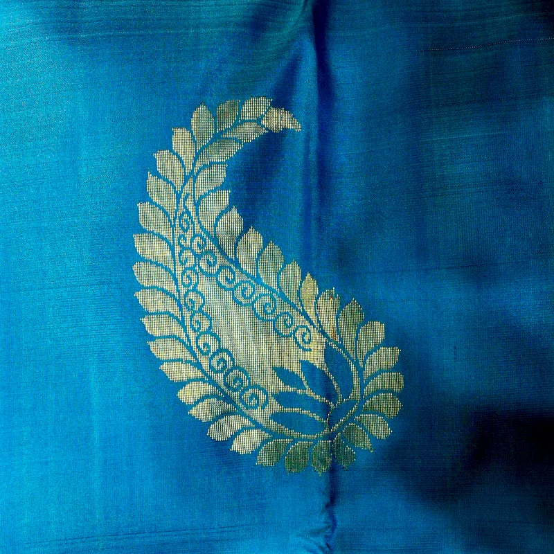 Kanchipuram silk in peacock blue, a gold mango buti woven into the cloth.