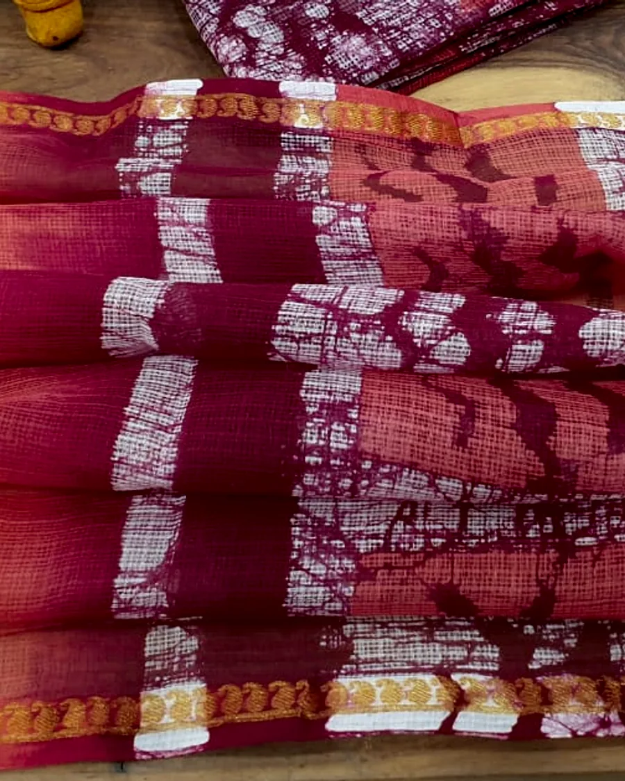 Kota doria in coral and madder, its open square-check weave visible against the light.