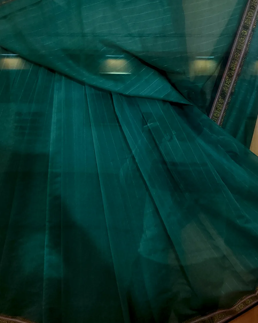 A teal Maheshwari sari showing its fine stripes and reversible zari border.