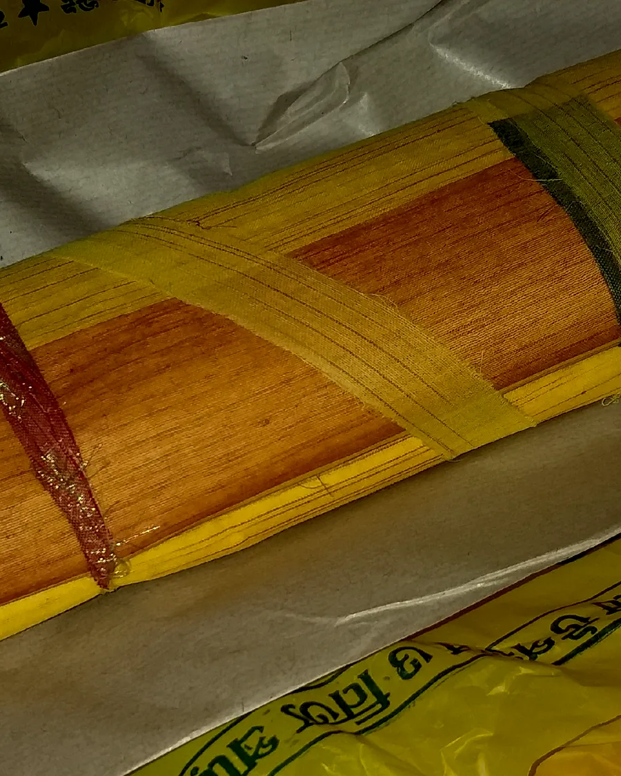 A folded Bengal tant sari in mustard cotton with a fine woven border.